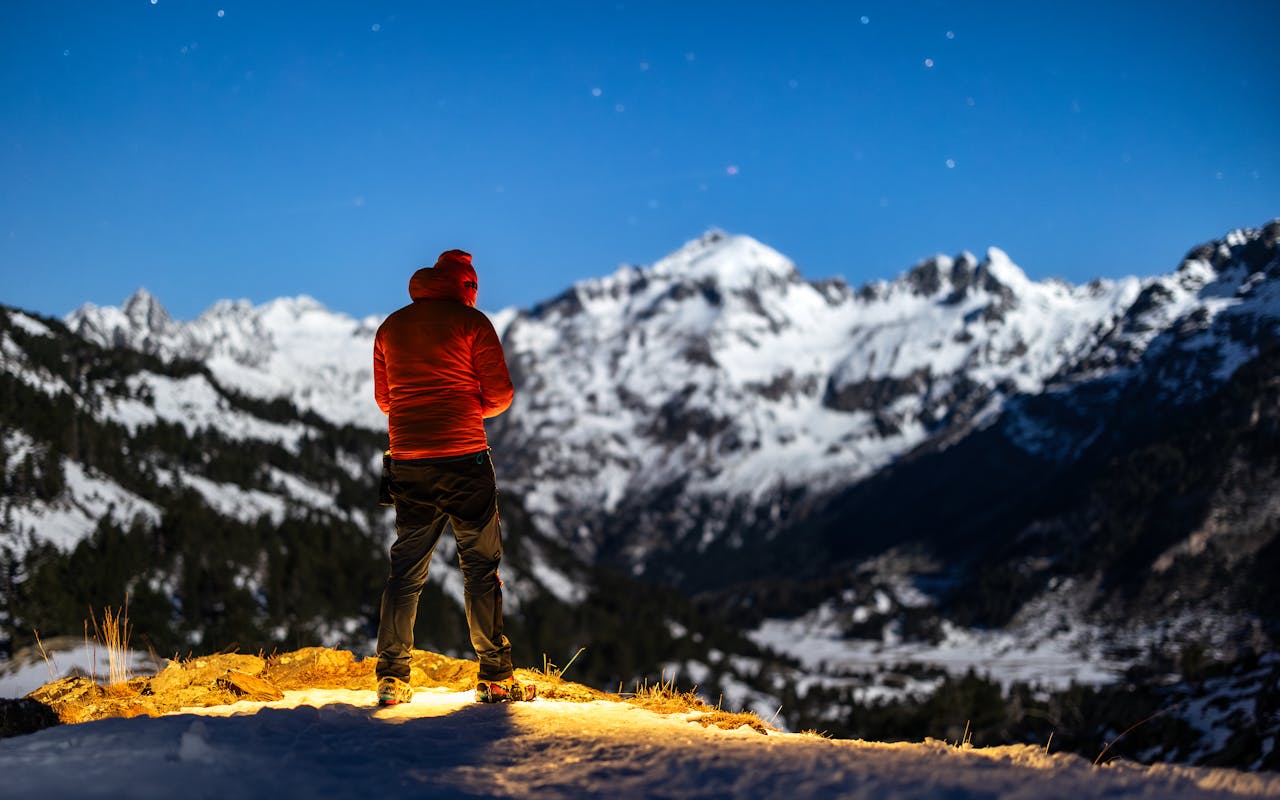 a person standing on a mountain looking at the snow covered mountains 27979602